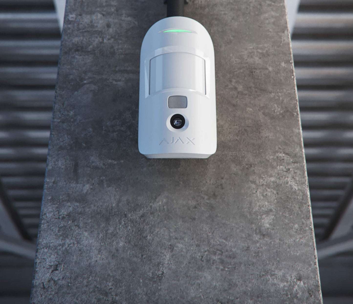 White Ajax MotionCam a wireless motion detector with a built in camera for home and business security, 110 × 65 × 50 mm in size, 86 grams in weight.Mounted to a wall in a warehouse for business security front view of device